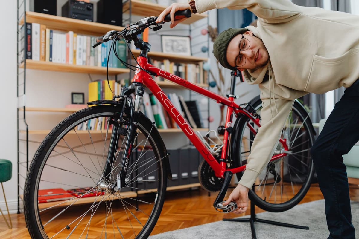 Ein junger Mann schraubt an einem roten Fahrrad, das in einem Montageständer steht.